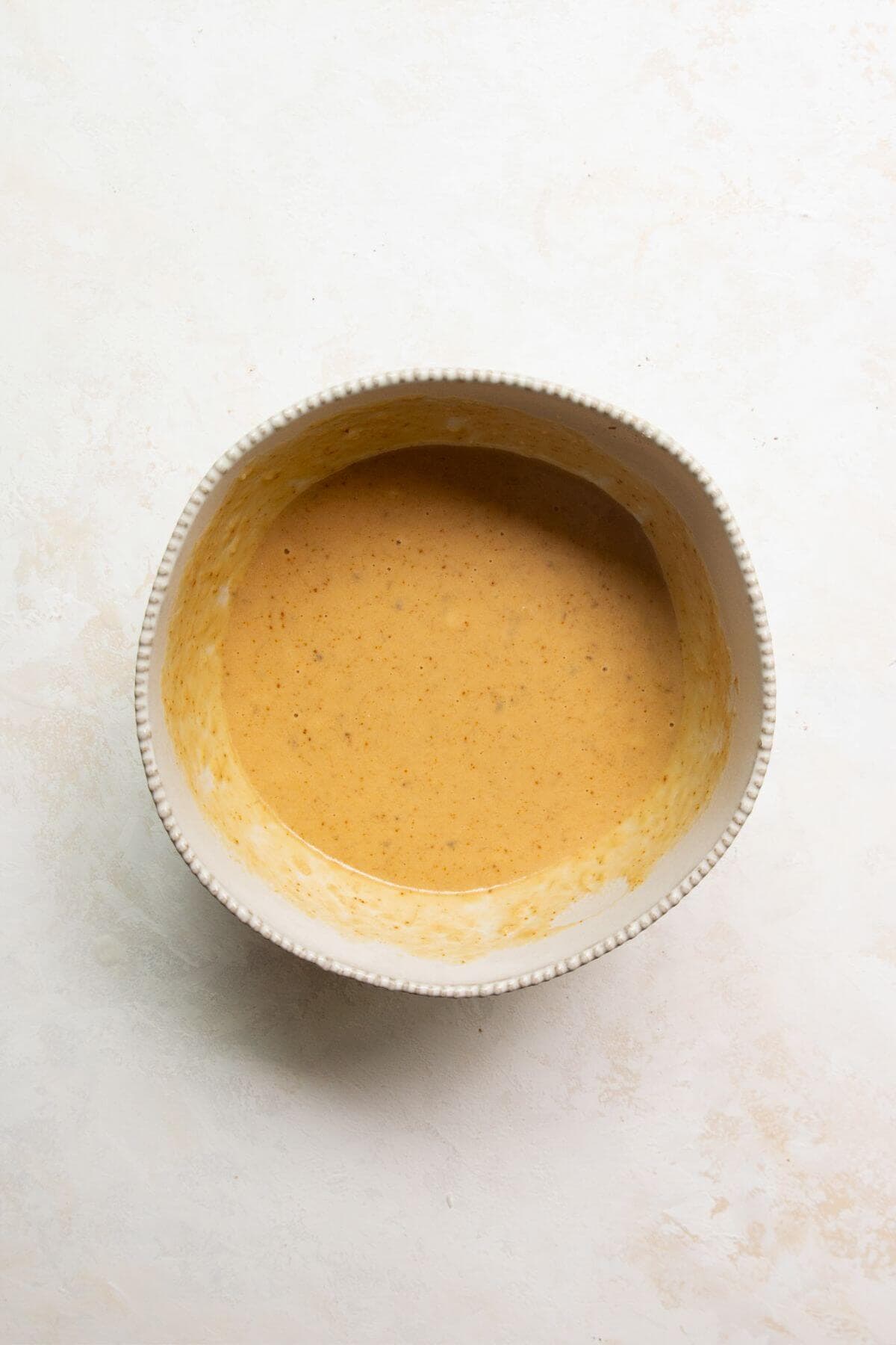 Wet ingredients for chocolate banana muffins whisked together in a mixing bowl.