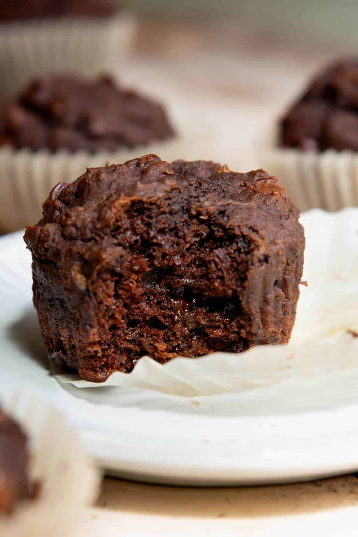 Moist chocolate banana muffin with a bite taken out, showing fudgy interior.