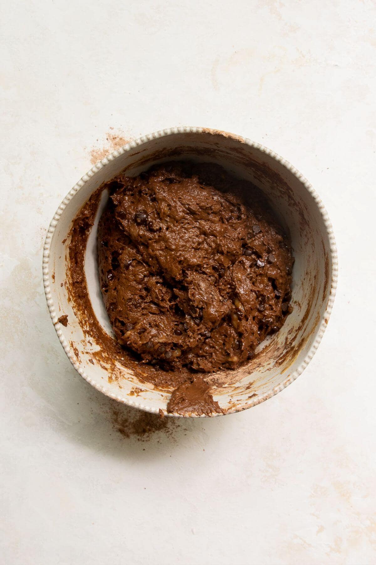 Thick chocolate banana muffin batter mixed in a mixing bowl.