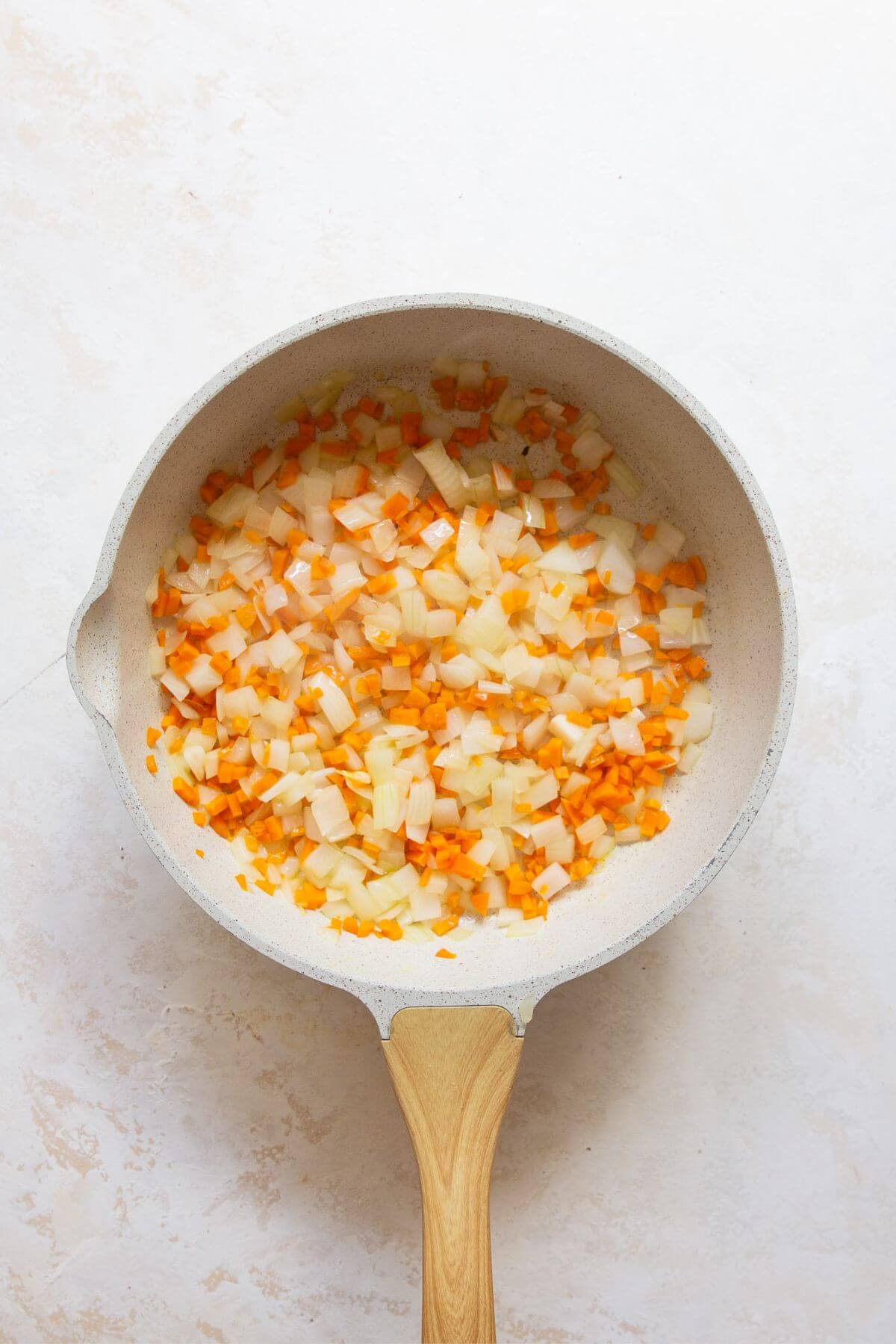 Onion and carrot cooking in a skillet until soft for homemade sloppy joe sauce.