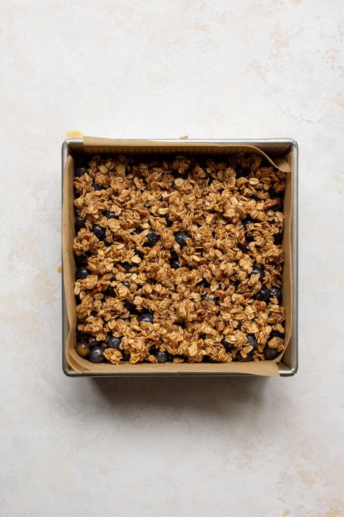 Sprinkling oat crumble topping over blueberries.