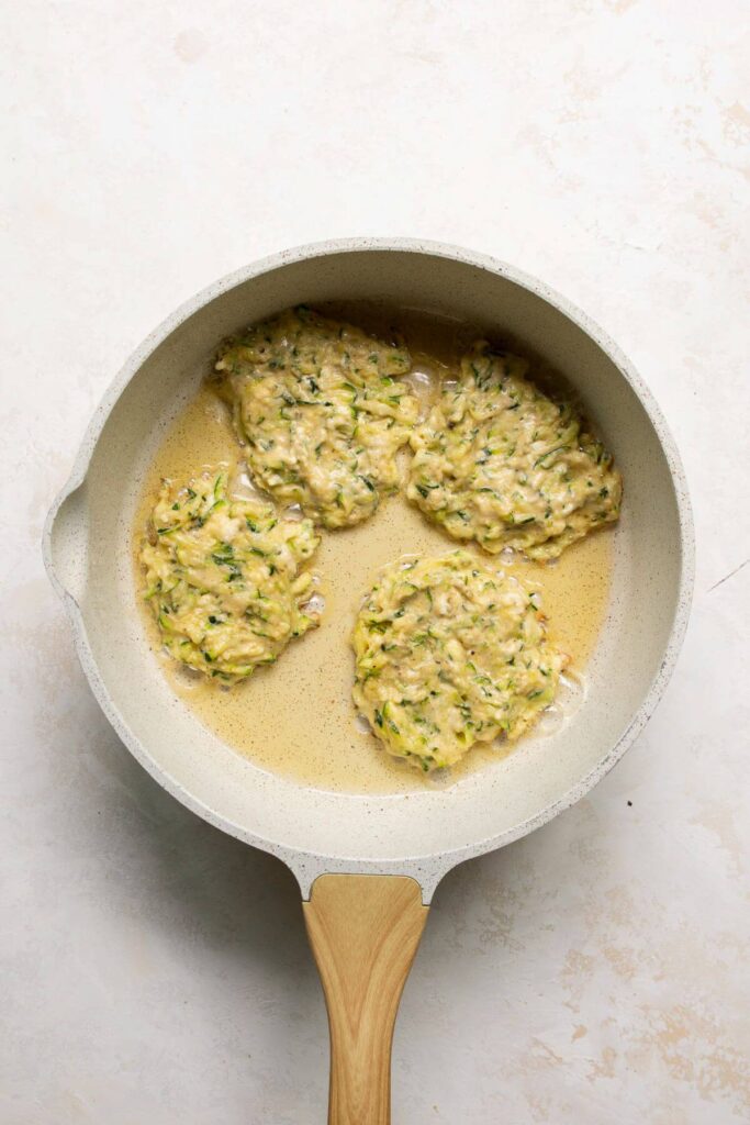 zucchini fritter batter in a pan with hot olive oil