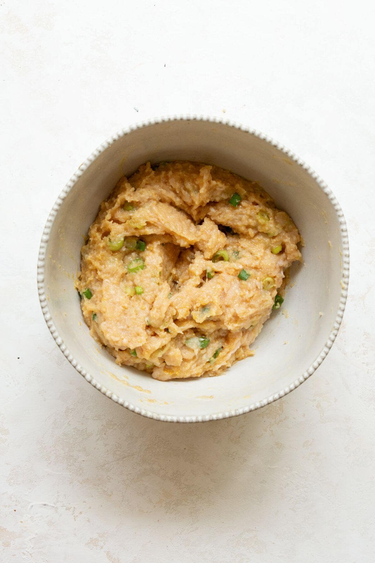 Mixing ground chicken with breadcrumbs egg garlic and ginger for burgers.