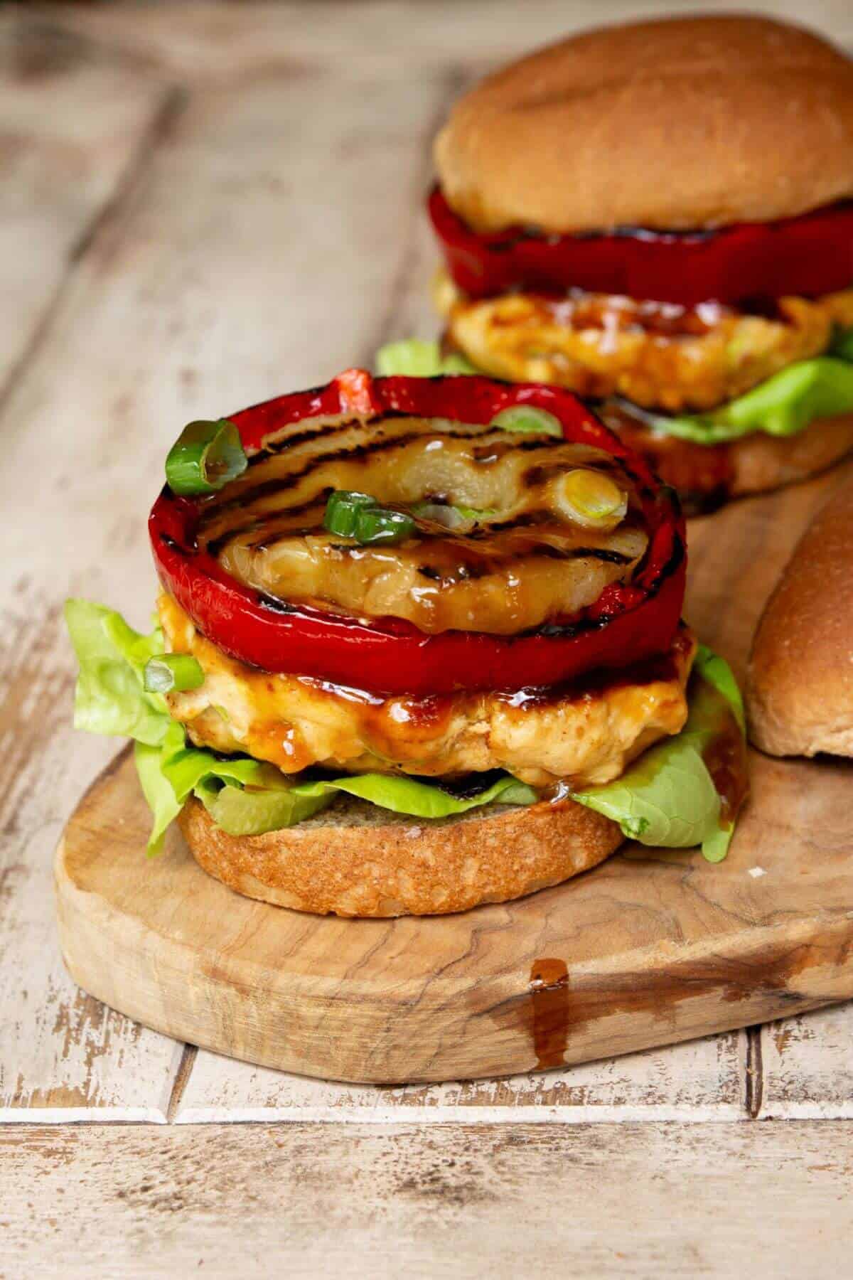 Close up of juicy chicken burger with caramelized pineapple and sauce.