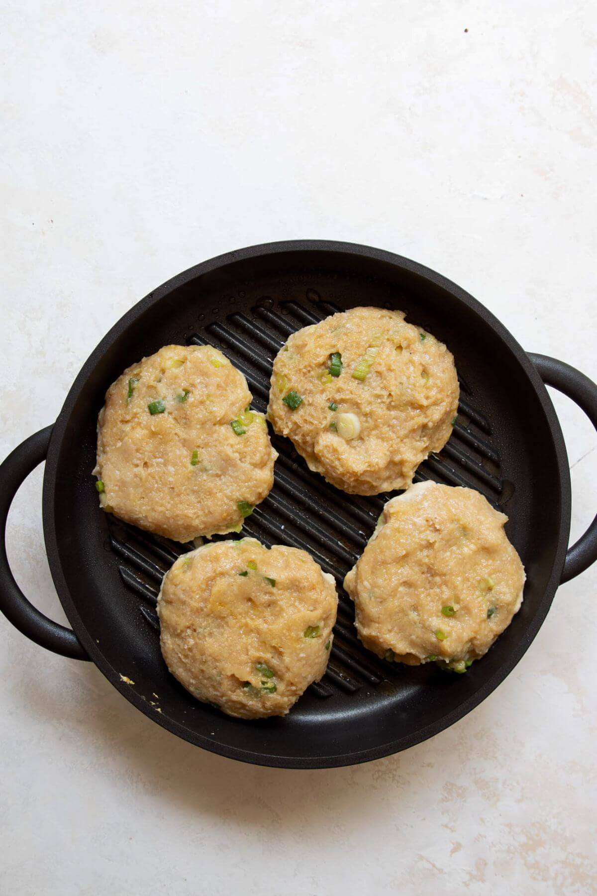 Grilling teriyaki chicken burger patties on grill pan.