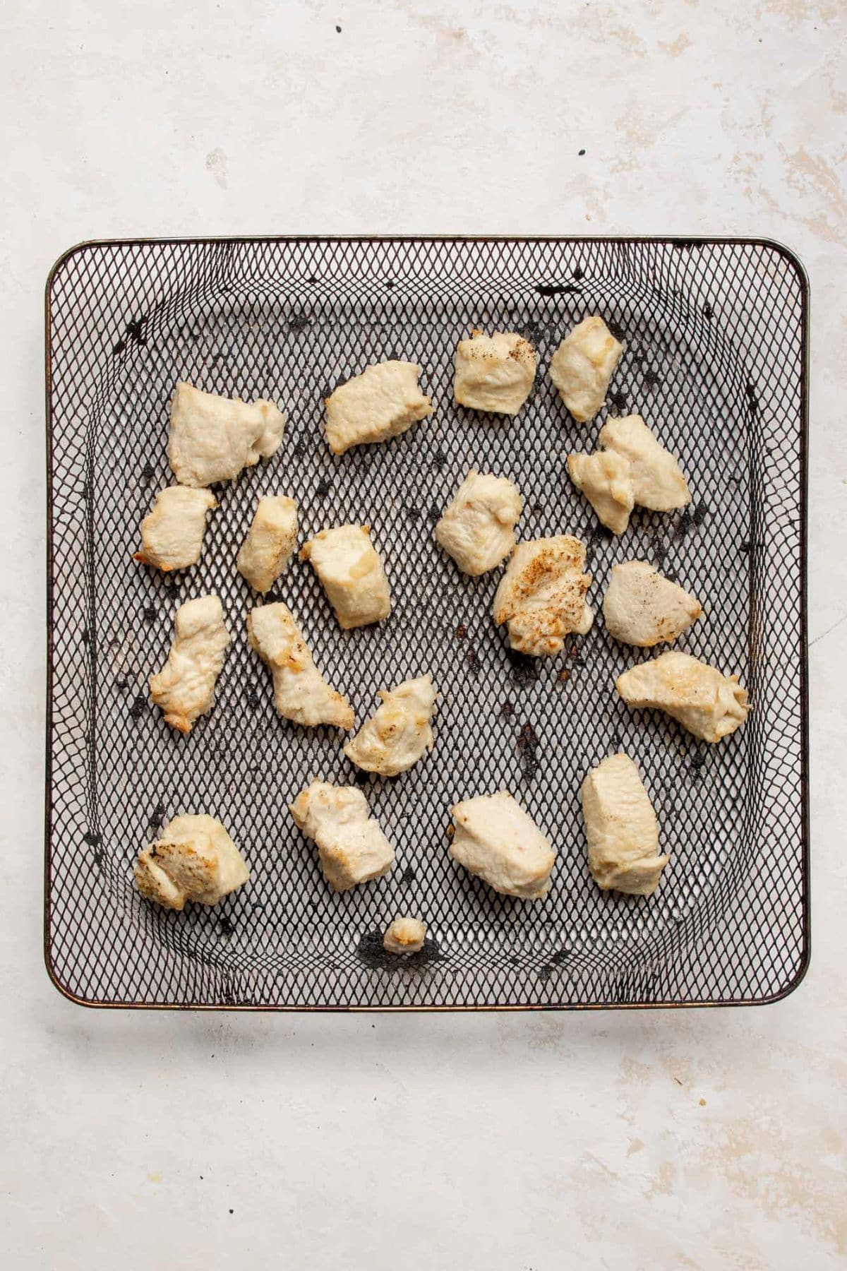 Crispy golden chicken bites in an air fryer basket after cooking.