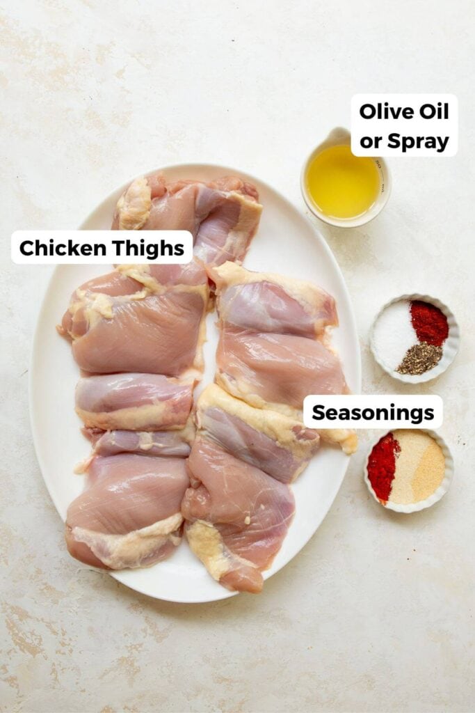 all ingredients in small bowls including boneless and skinless chicken thighs, spices, and olive oil