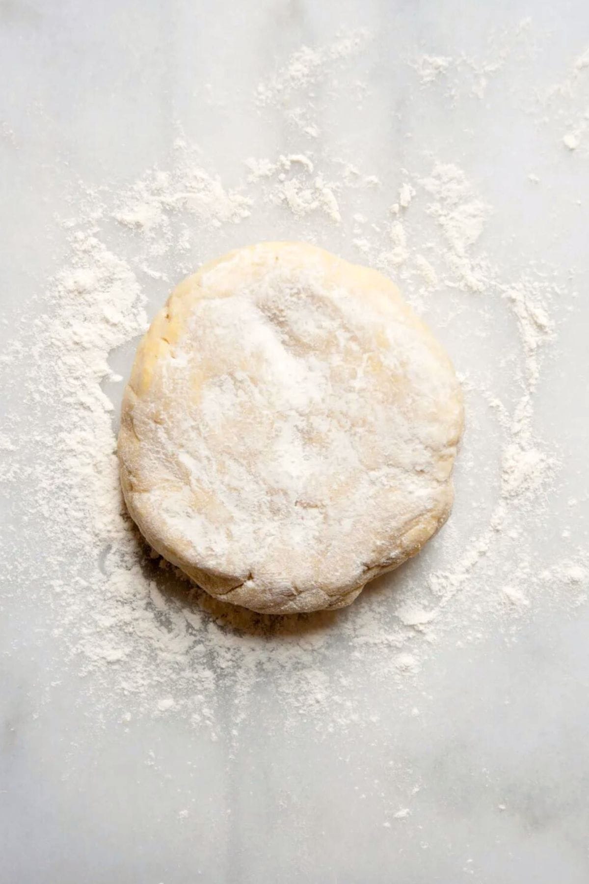 Lightly flouring a chilled gluten-free pie crust shaped into a disc.