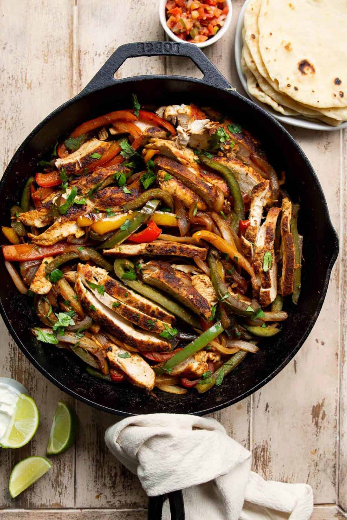 Healthy skillet chicken fajitas with onions, bell peppers, and juicy chicken breast.