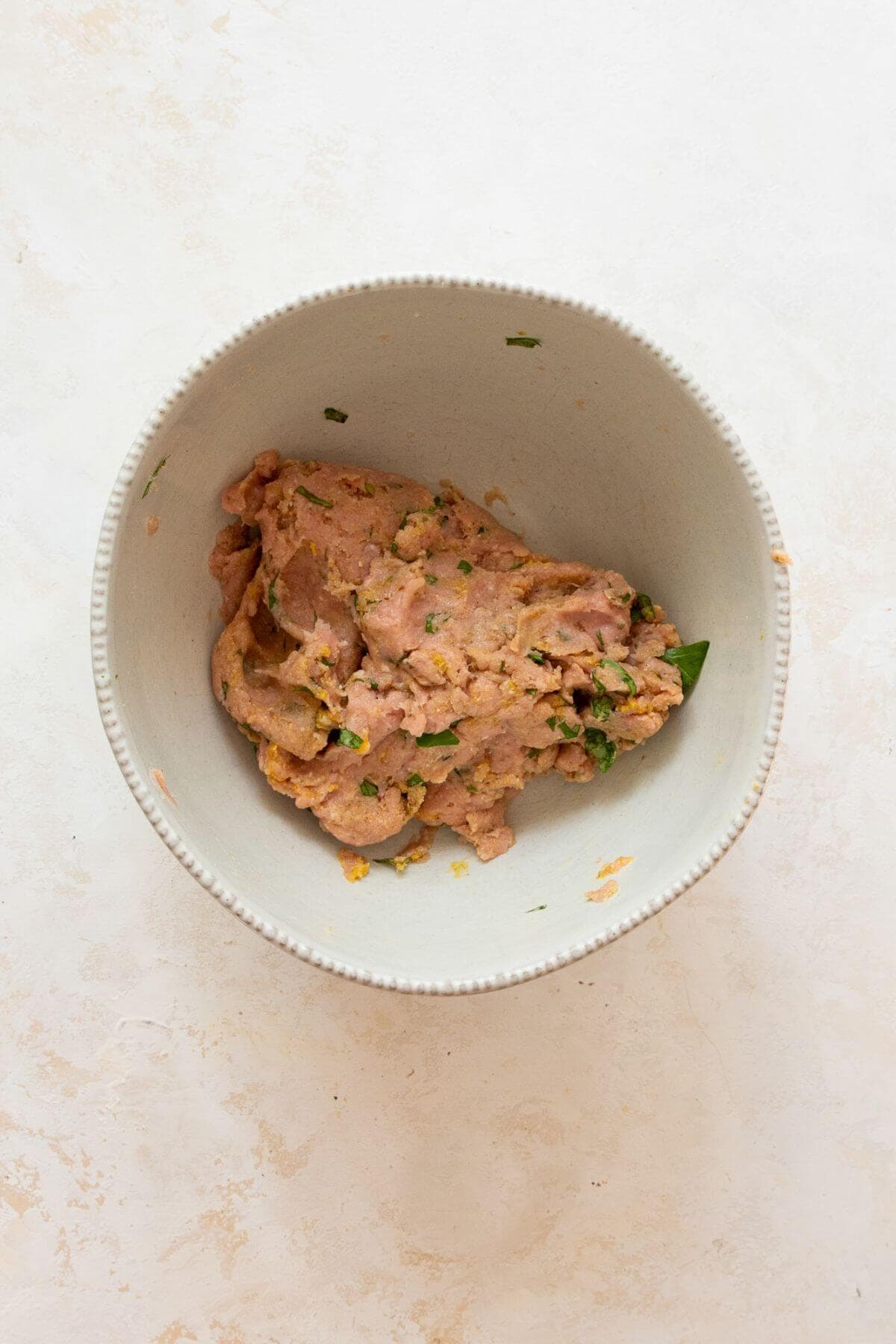 Ground turkey meatball mixture in a bowl with all the seasonings.