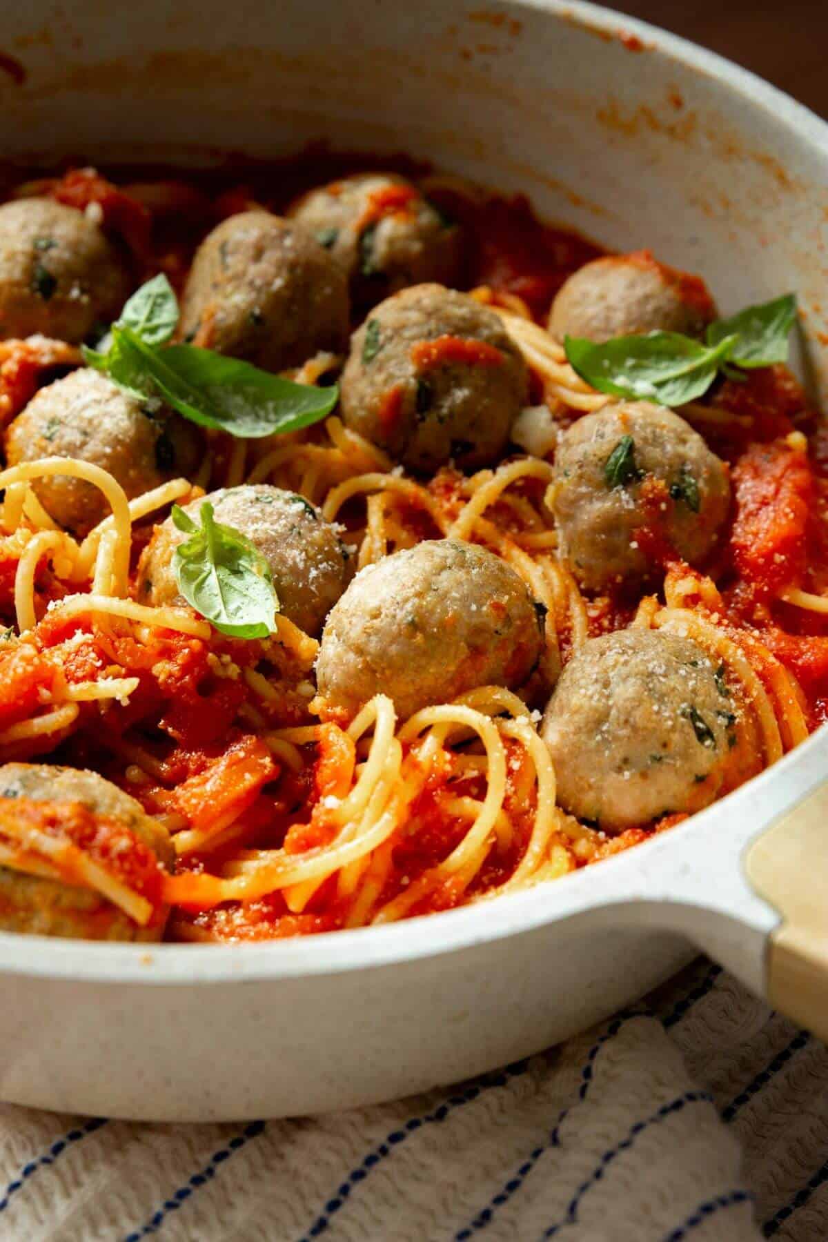 Finished air fryer turkey meatballs in a pan with pasta and red sauce.