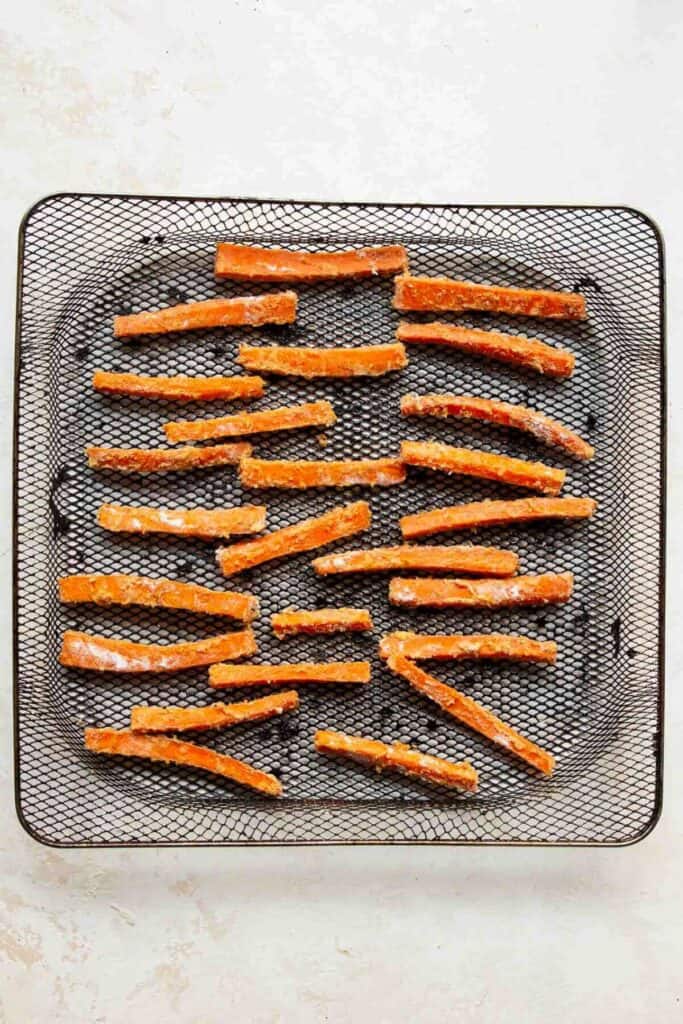 seasoned carrot stick in air fryer basket before cooking