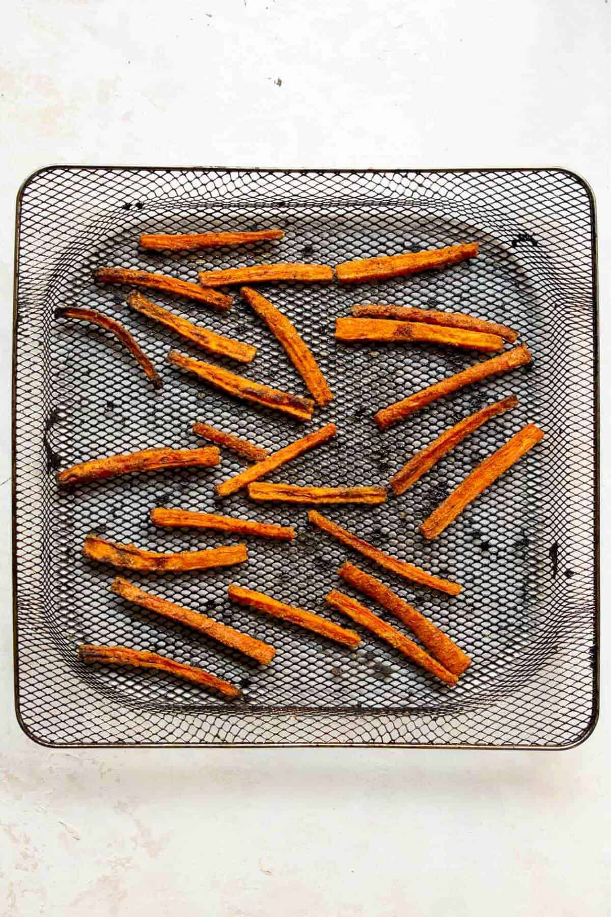 Crispy carrot fries in air fryer basket after cooking.