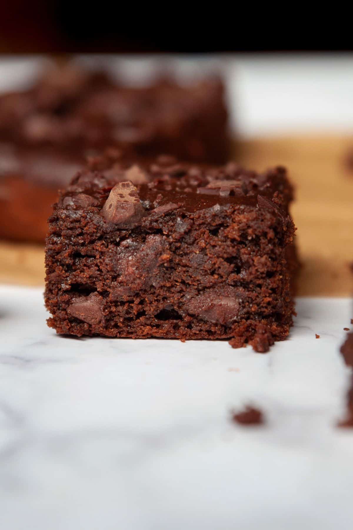 Side view of fudgy, thick flourless brownies with chocolate chips.