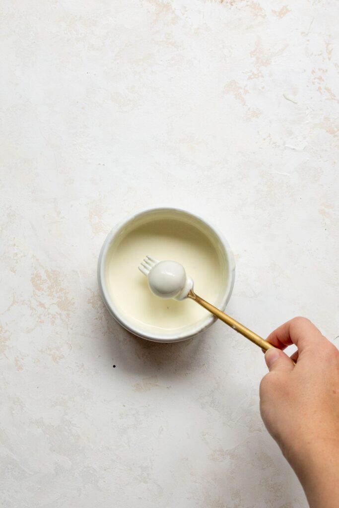 dipping birthday cake truffles in melted white chocolate