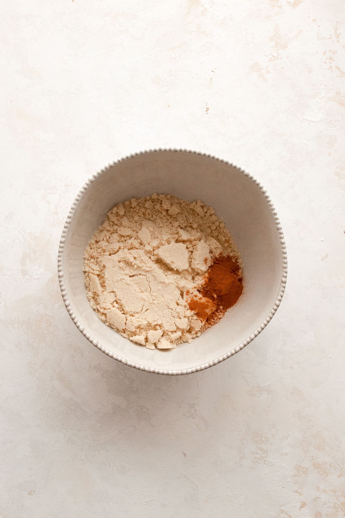 Almond flour, cinnamon, and baking powder whisked together in a small white bowl.