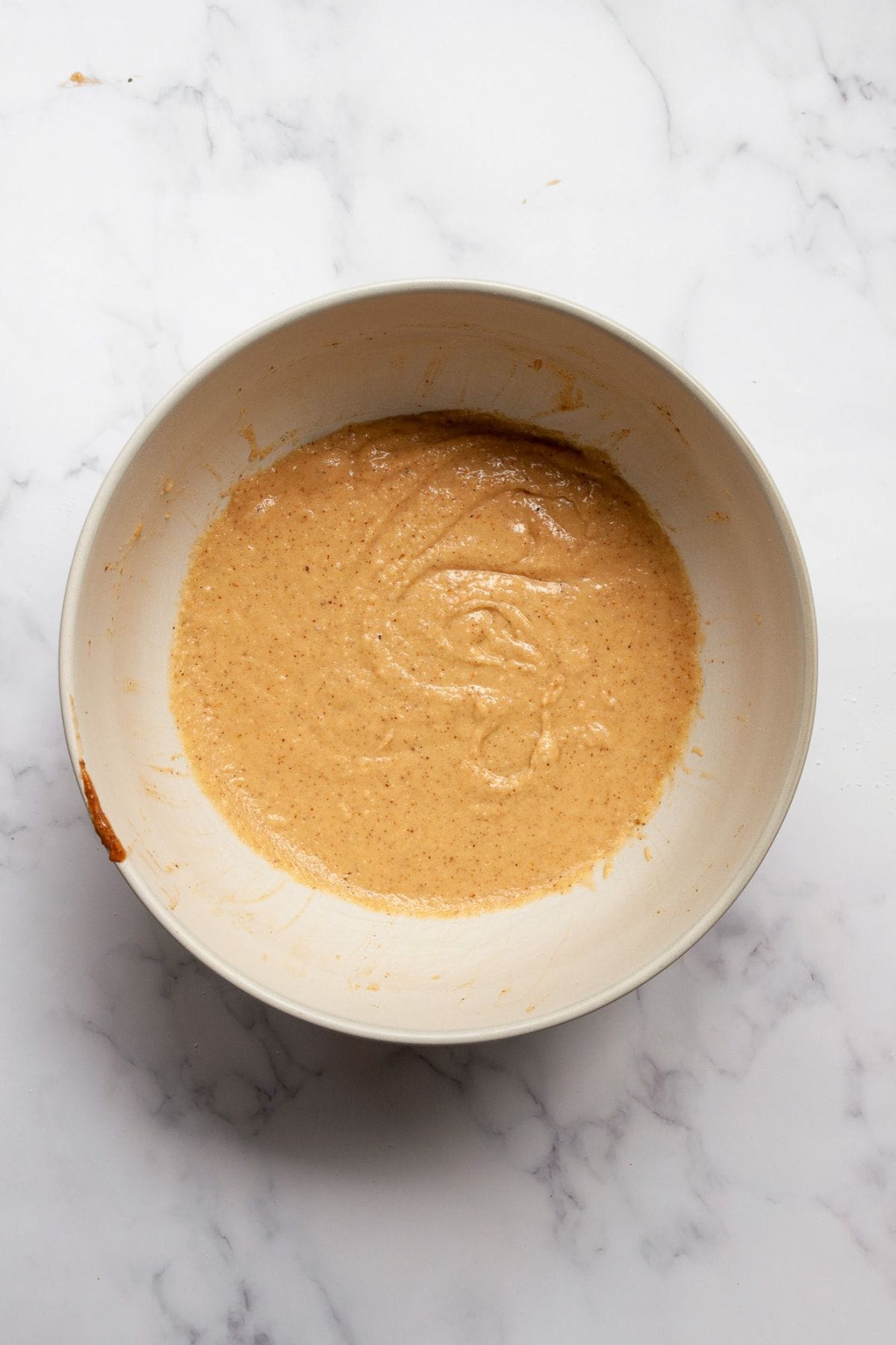 Smooth almond flour waffle batter mixed in a white bowl, ready to pour into the waffle iron.