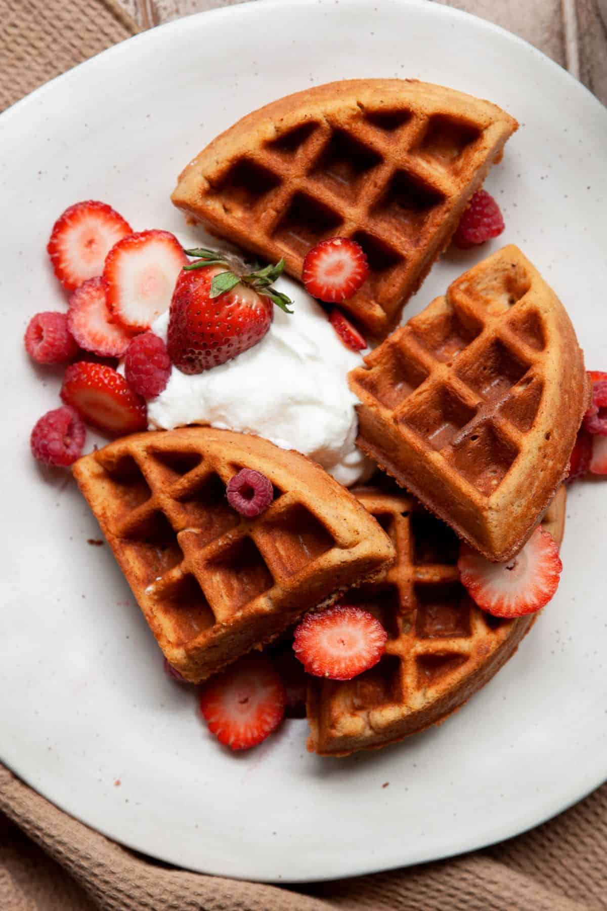 Keto almond flour waffles topped with whipped cream and fresh strawberries.