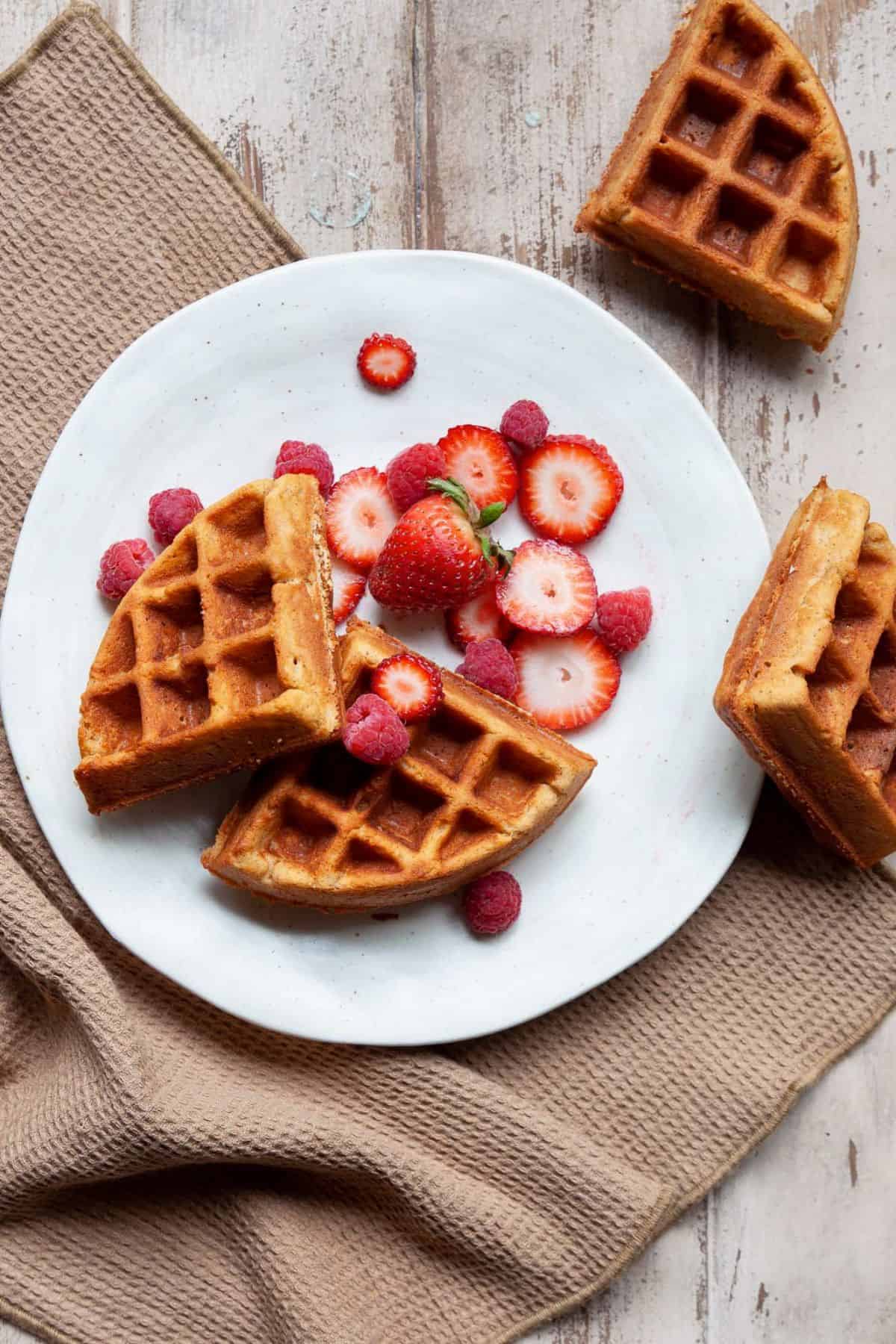 Plated almond flour waffles topped with fresh strawberries and raspberries.
