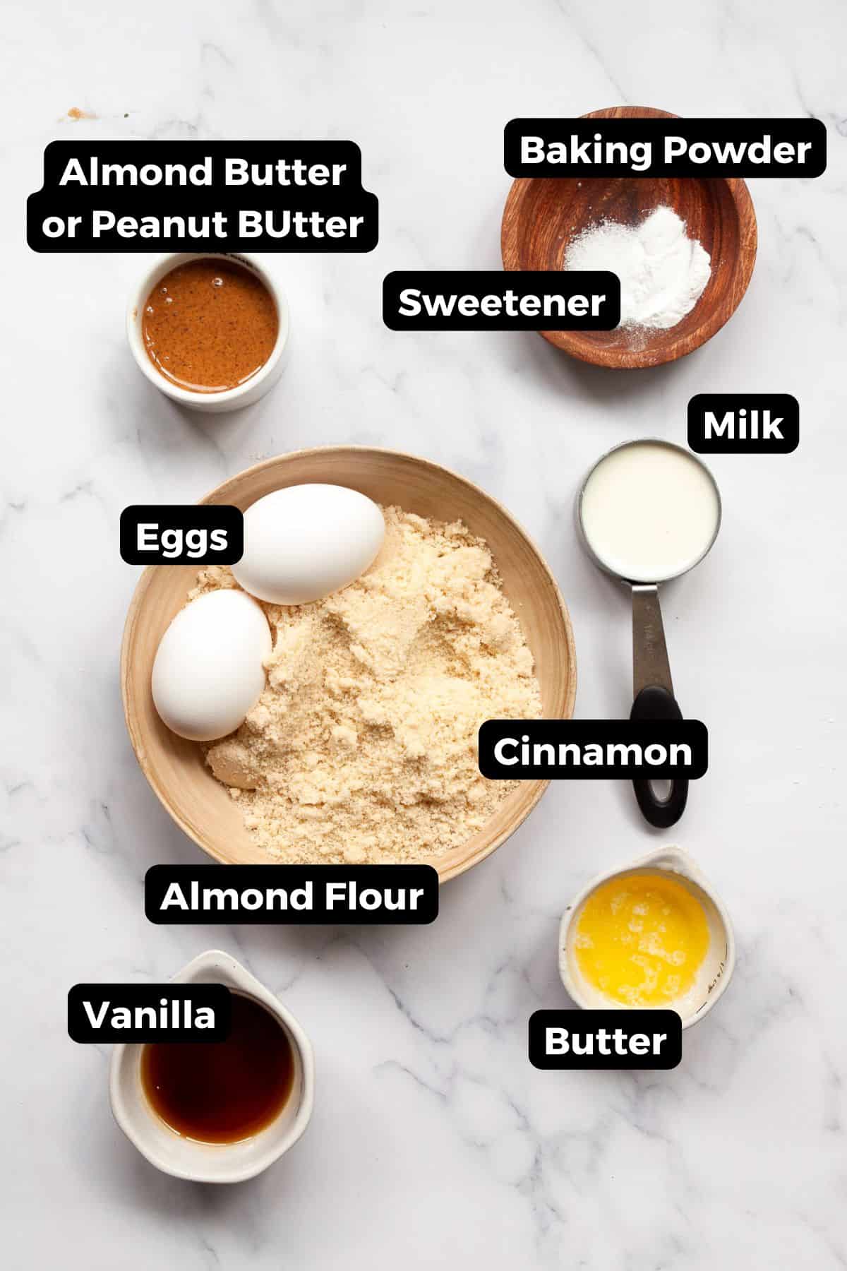 Labeled ingredients for almond flour waffles including almond flour, eggs, peanut butter, almond milk, butter, baking powder, sweetener, cinnamon, and vanilla.