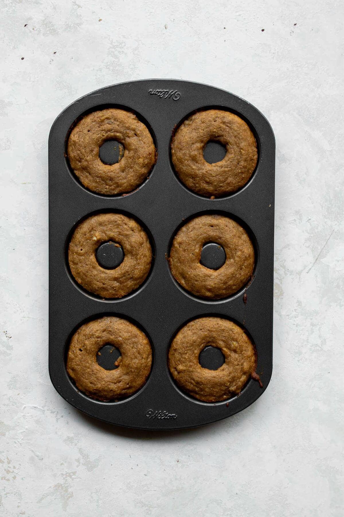 Baked banana bread donuts cooling in the donut pan