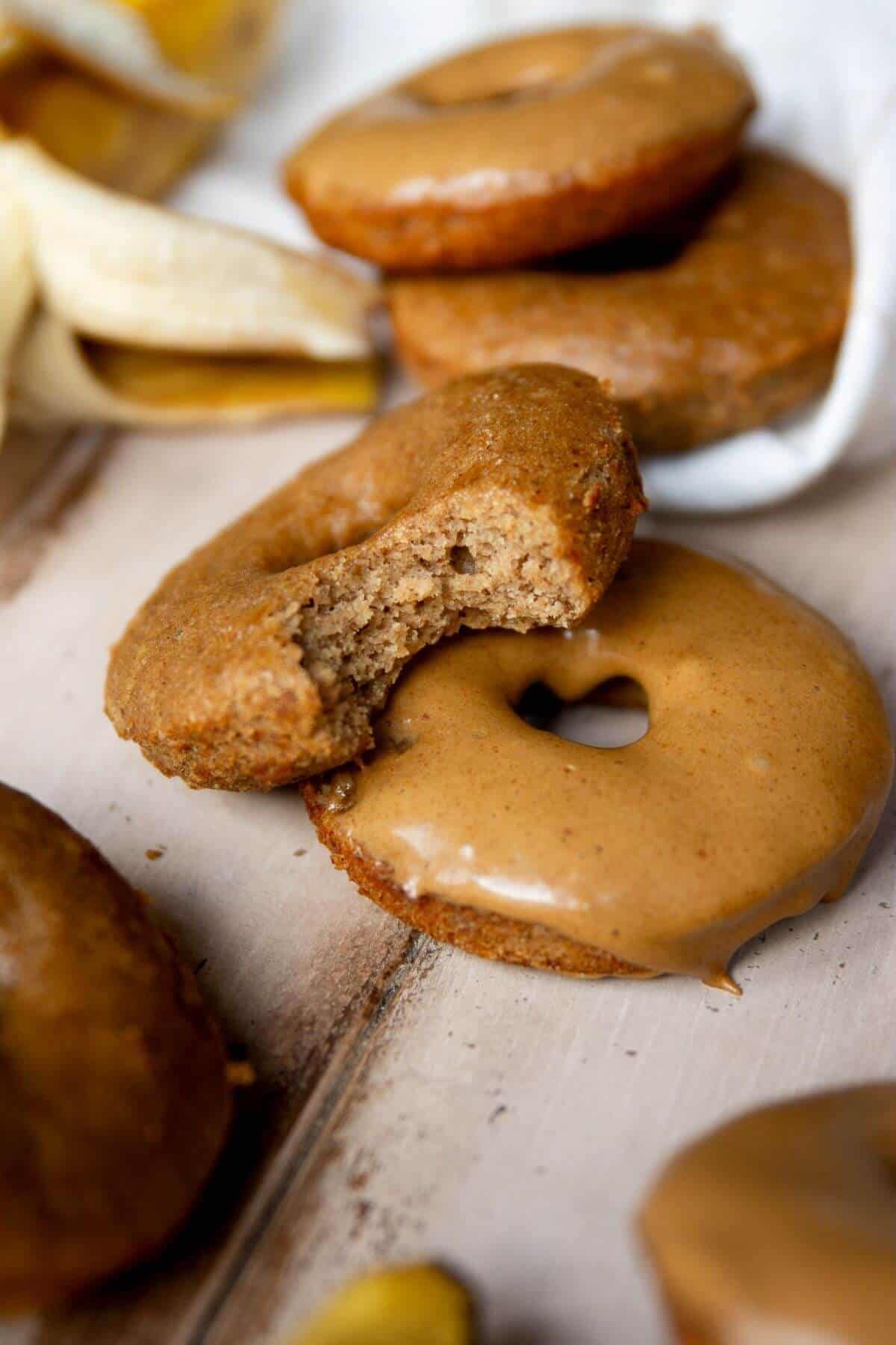 Healthy banana bread donut with a bite taken out showing the soft, fluffy inside.