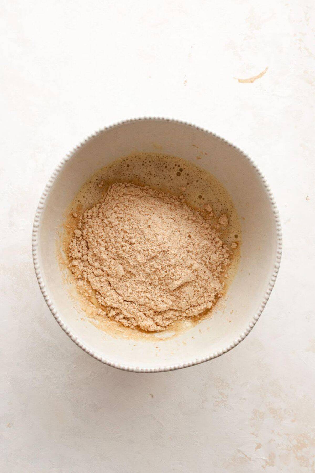 Mixing dry and wet ingredients together to form banana bread batter.