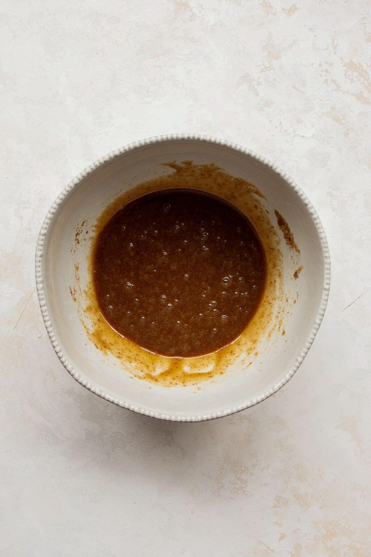 Melted coconut oil and coconut sugar whisked together in a bowl.