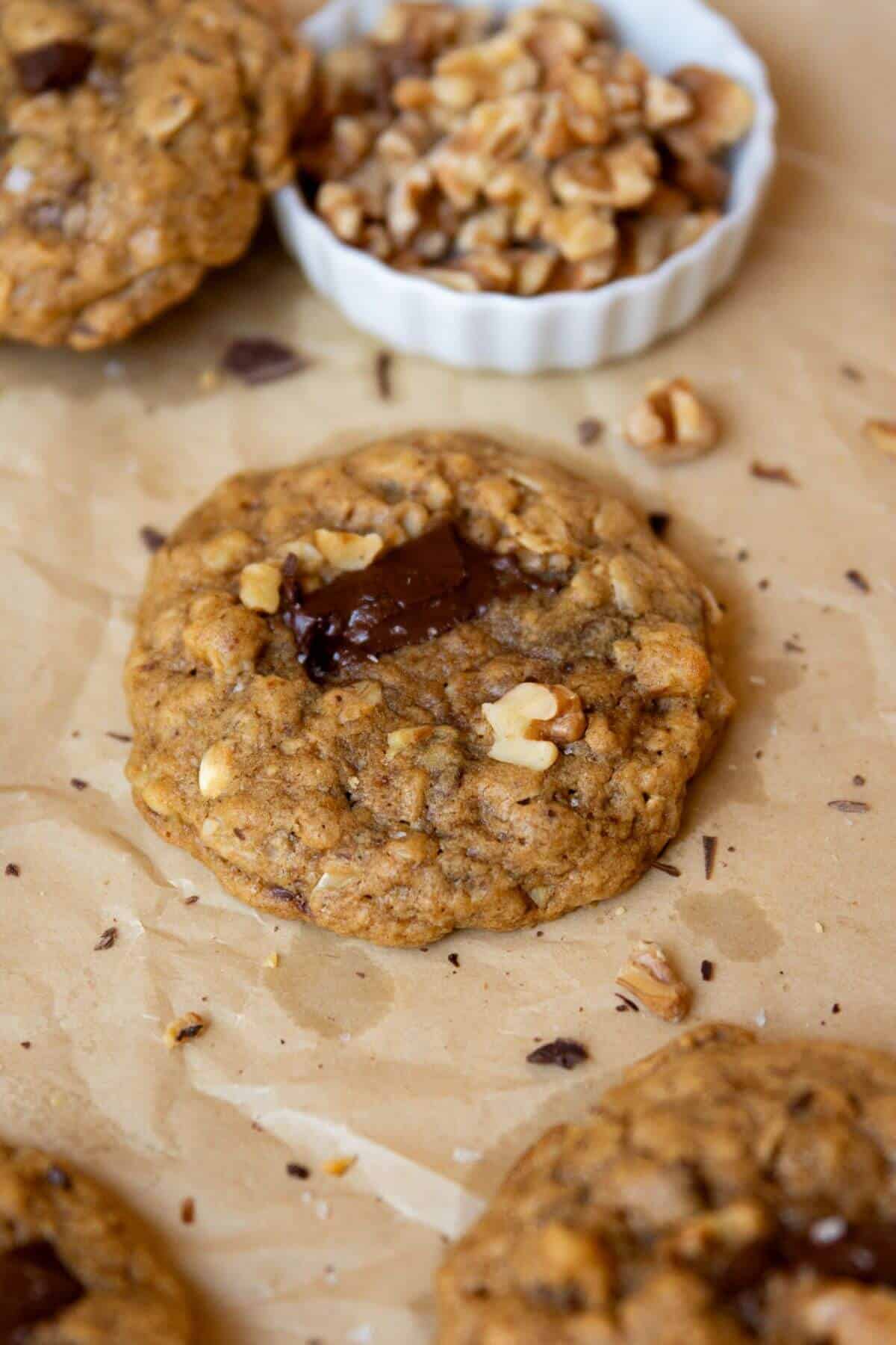 Close-up of a chewy, gluten-free oatmeal cookie with melted chocolate and toasted walnuts.