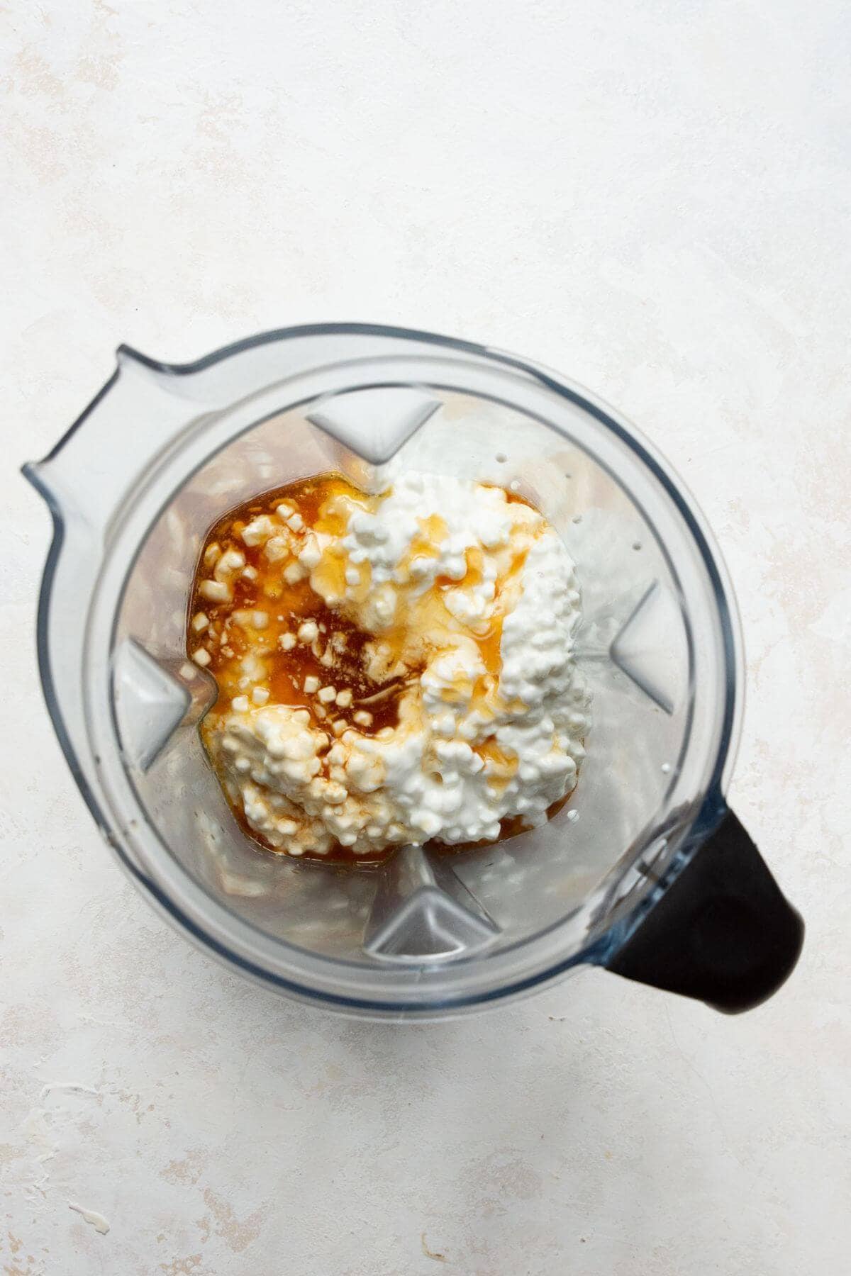 Cottage cheese, vanilla, and honey in a blender before blending.