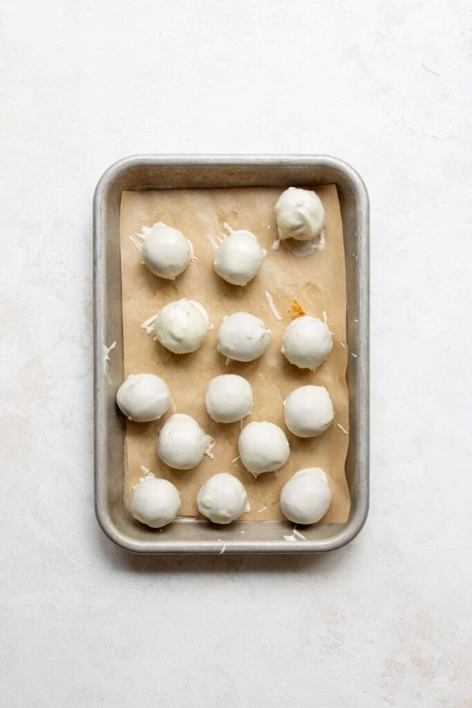 pumpkin spice truffles on a baking sheet after being dunked in white chocolate