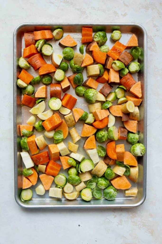 cut up sweet potatoes, Brussels sprouts, carrots and parsnips on a baking sheet with olive oil, minced garlic, and salt before roasting
