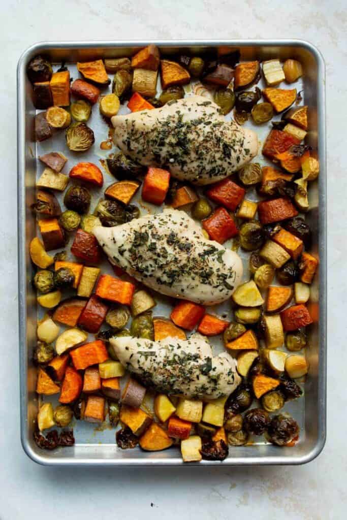 roasted chicken and crispy Brussels sprouts, carrots, potatoes, and parsnips on a sheet pan