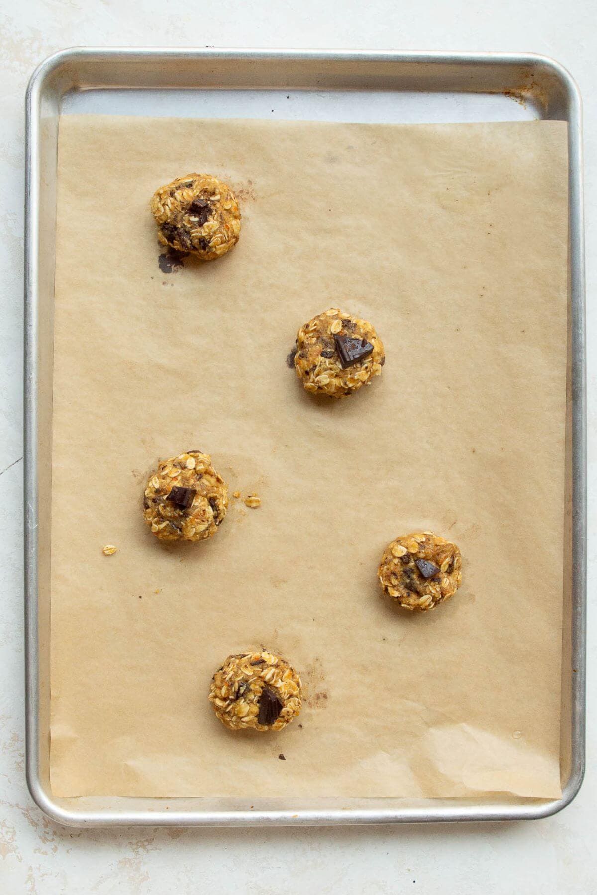 Cookie dough balls spaced out on a parchment-lined baking sheet.