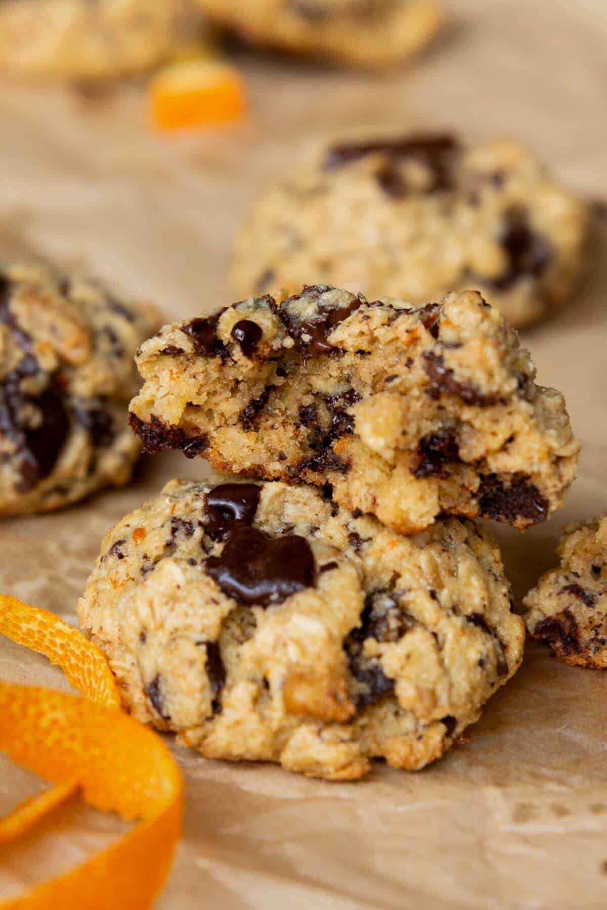 Stack of orange chocolate chip oatmeal cookies with a bite taken out, showing melted chocolate inside.