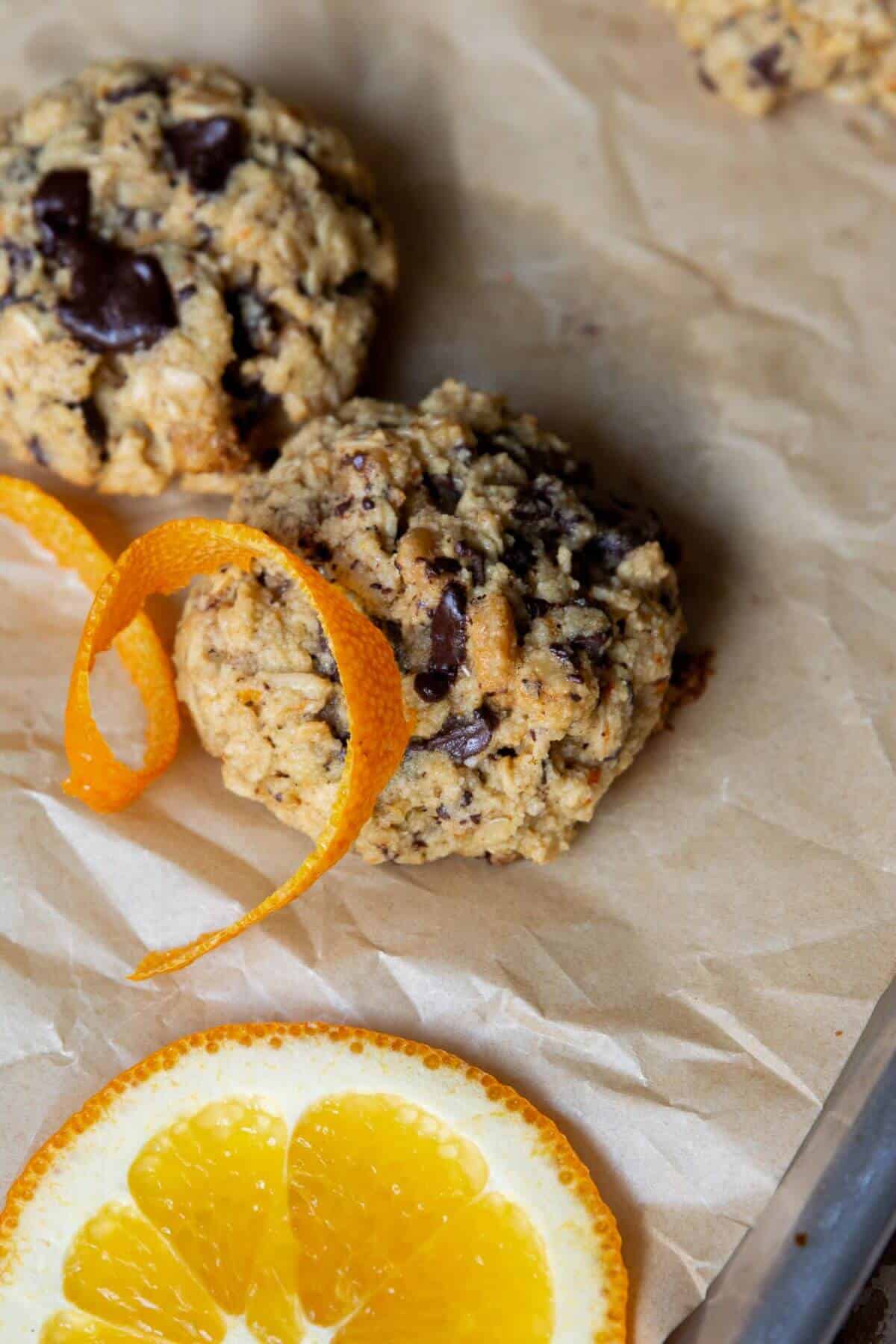 Orange oatmeal cookies with a curl of orange peel and a fresh orange slice.