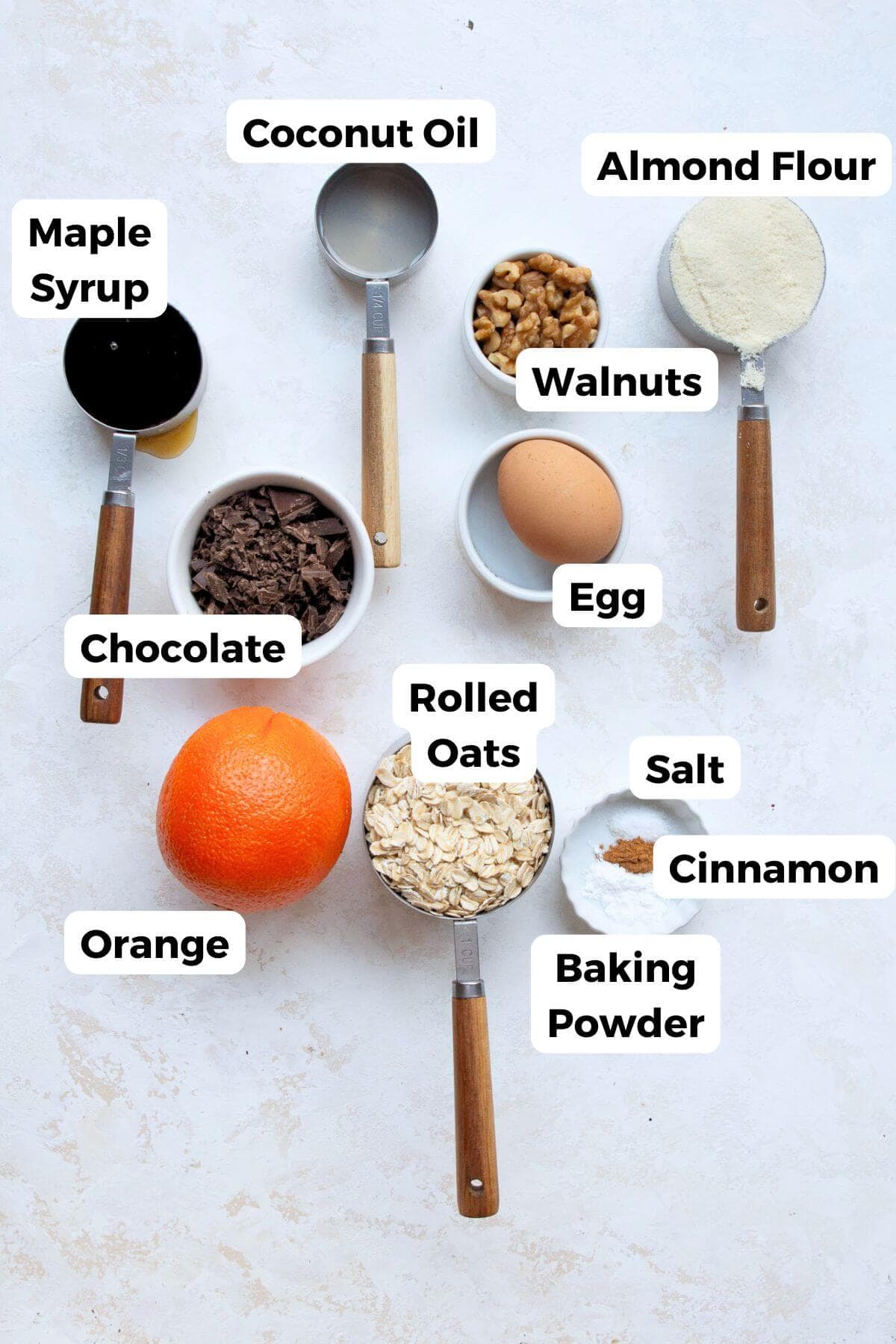 Ingredients for orange chocolate chip oatmeal cookies, including oats, almond flour, maple syrup, and a fresh orange.
