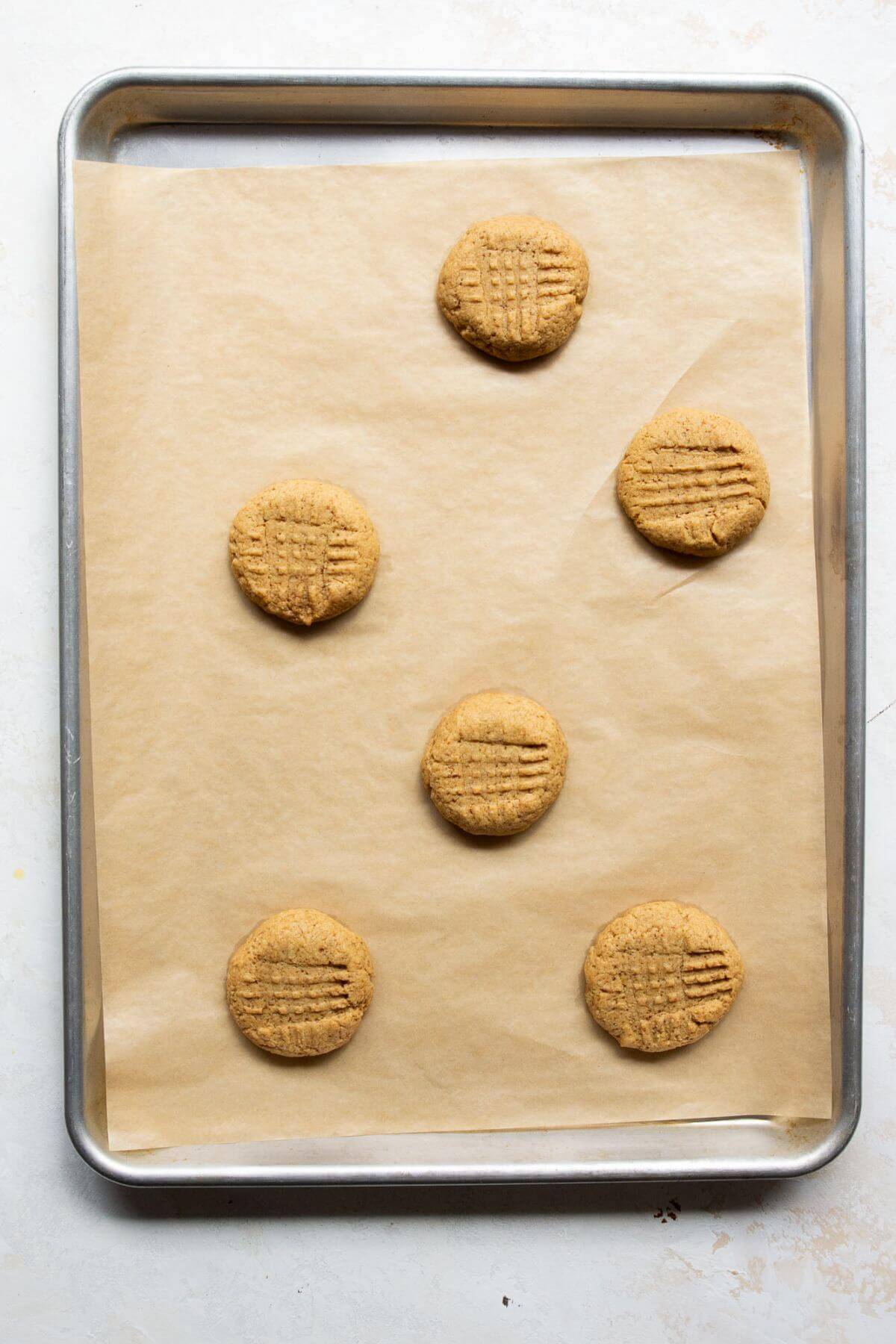 Freshly baked almond flour peanut butter cookies with golden edges cooling on a parchment-lined baking sheet.