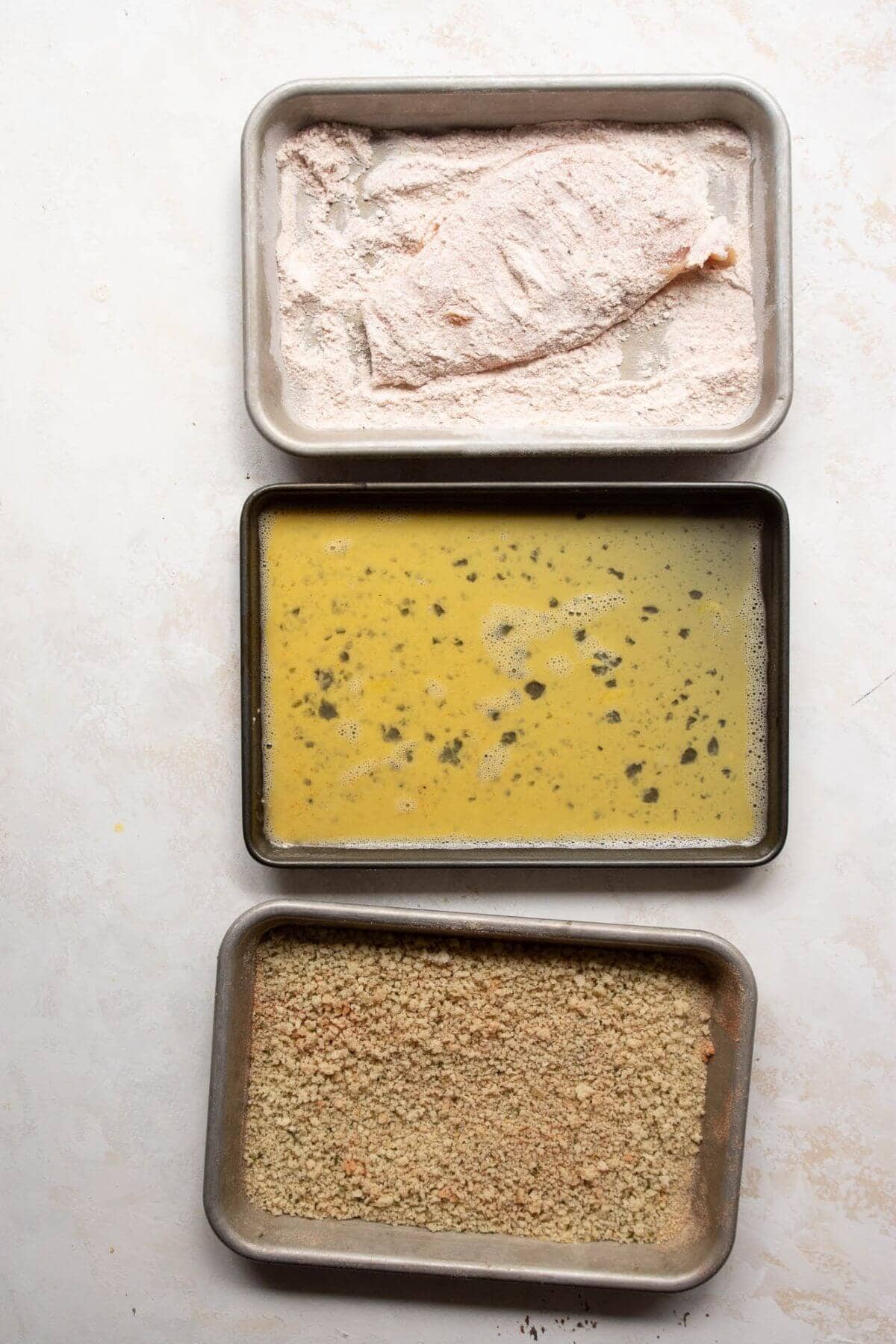Dredging raw chicken cutlet in flour.