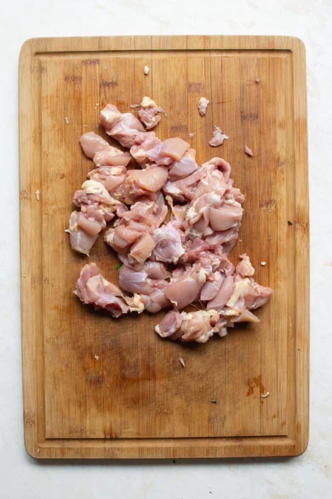 cutting up chicken thighs into bite sized pieces before cooking