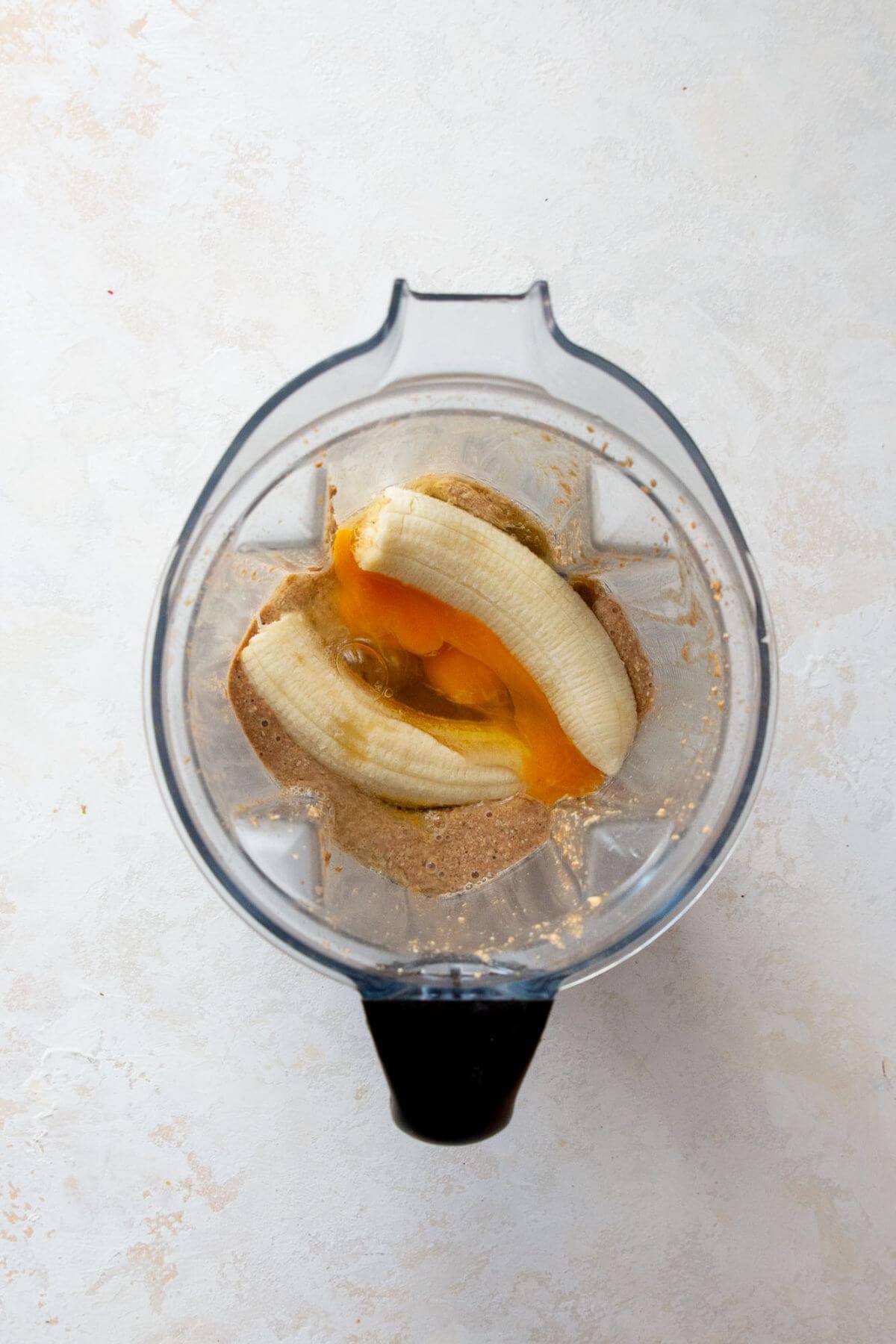 adding banana, eggs, maple syrup, milk, and vanilla to the blender