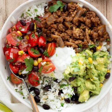 healthy ground beef burrito bowls with guacamole, beans, cilantro lime rice, and salsa