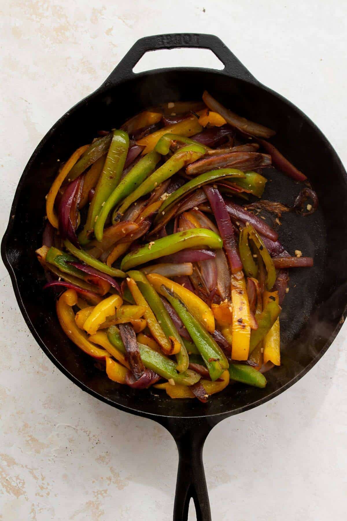 In the same pan, cooking onions, bell peppers, garlic, cilantro, and a pinch of salt