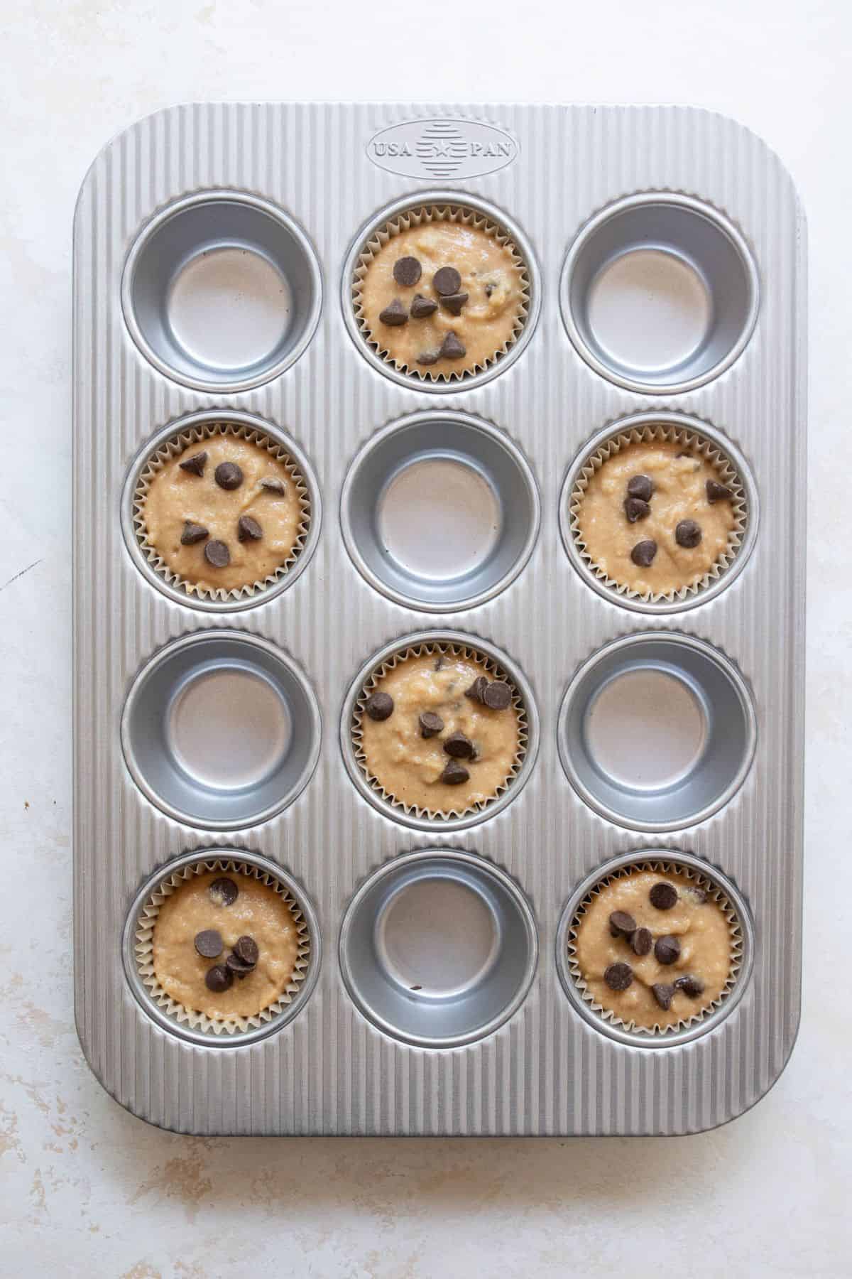 unbaked banana protein muffins with chocolate chips in a muffin tin before baking
