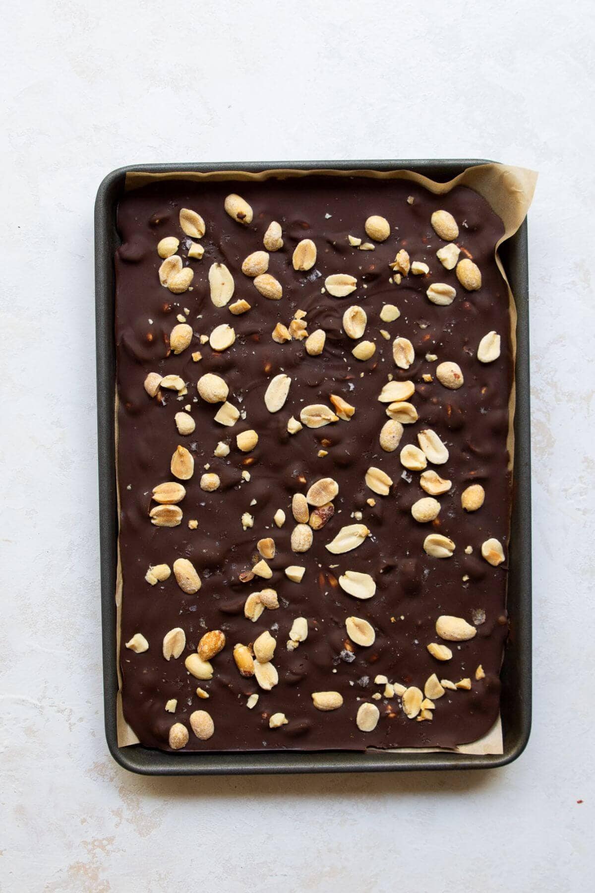 dark chocolate peanut bark on a baking sheet