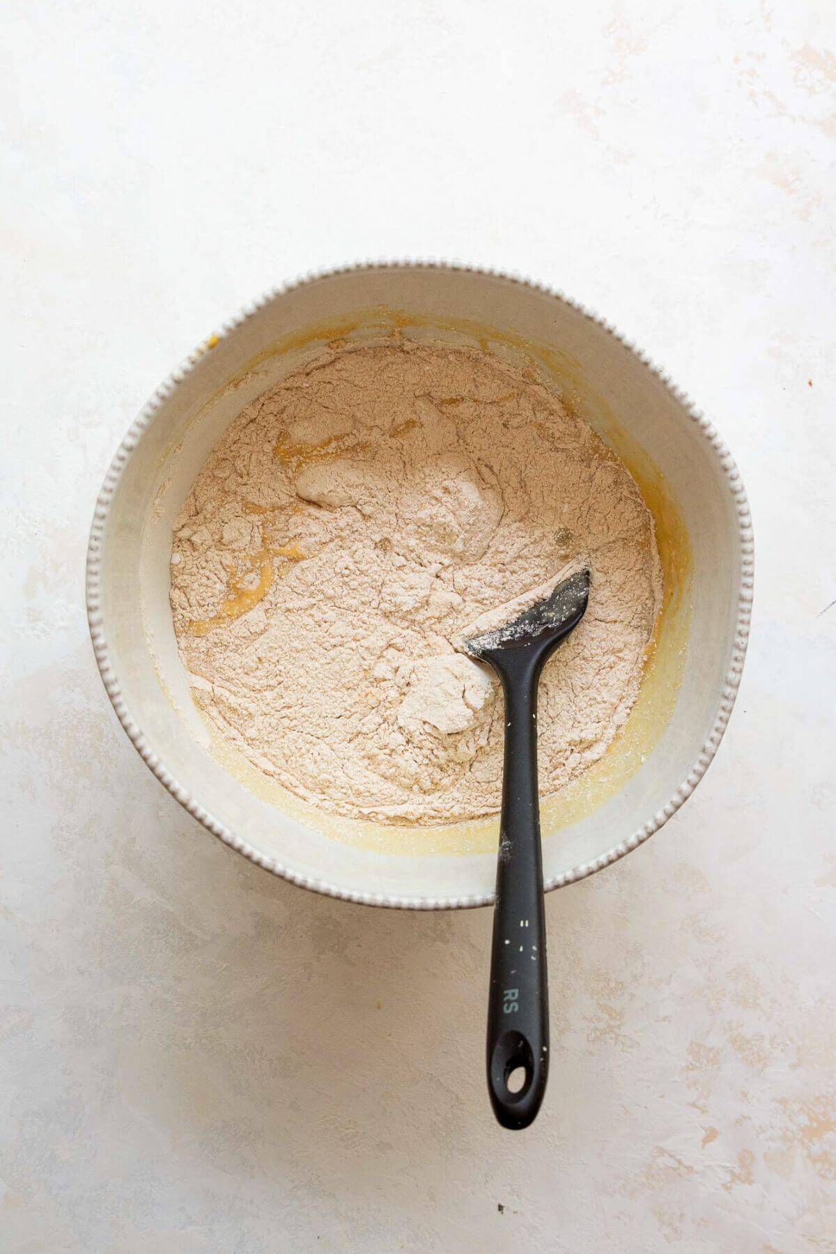 adding white whole wheat flour, baking soda, salt, and baking powder to the wet ingredients in a bowl
