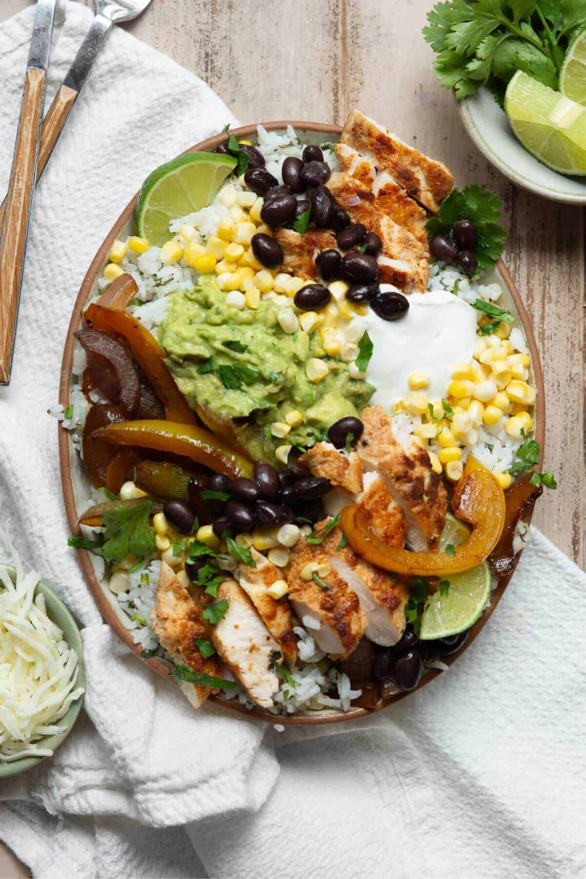Healthy chicken fajita and rice bowls with beans, corn, cilantro rice, and guacamole.