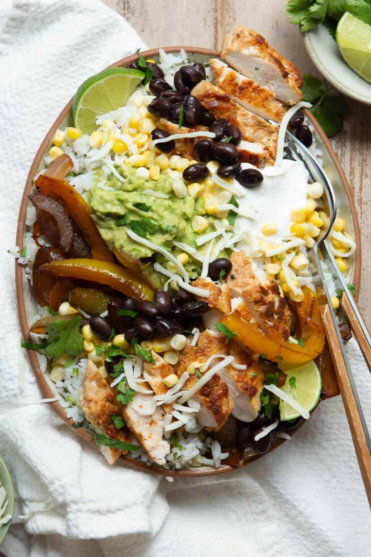 Healthy chicken fajita bowl with blackened chicken, cilantro lime rice, black beans, corn, and homemade guacamole.