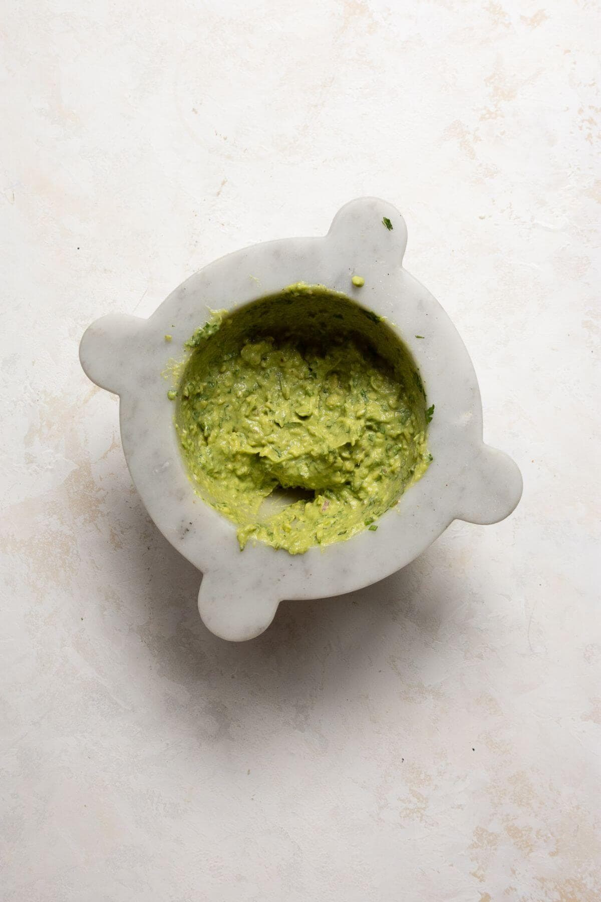 Homemade 4-ingredient guacamole mashed in a bowl for chicken fajita bowls.