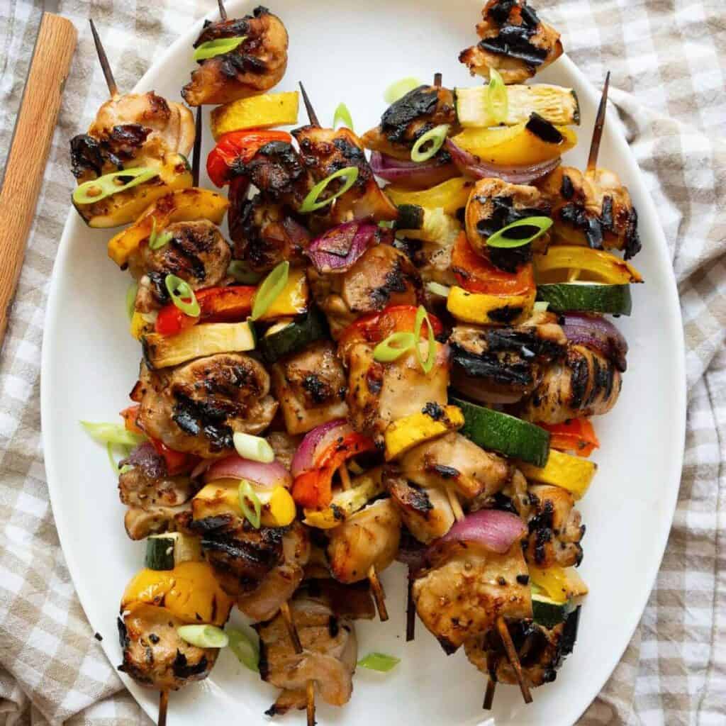 Grilled honey soy chicken kebabs served on a platter with colorful veggies, lightly charred and glossy from the miso marinade